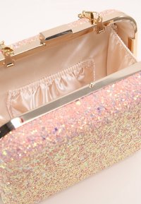 Glittrande rosa clutchväska med metallguld hårdvara. Insidan har en sidentygsatt läderfoder och en elastisk ficka för organisering.