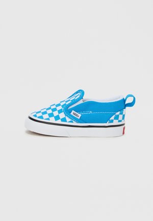 Chaussure Vans slip-on à damier bleu et blanc avec semelle blanche et bande noire, vue de côté sur un fond clair uni.