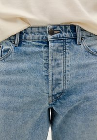 Blaue Jeans aus Denim mit hoher Taille, ausgestattet mit einem Frontknopfverschluss, dezentem Verblassen und klassischem Fünf-Taschen-Design.