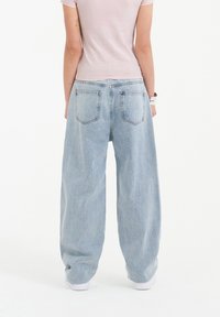 Light blue, wide-leg jeans with a high waist, featuring a five-pocket design and a subtle fade. Fabric appears soft with slight texture.