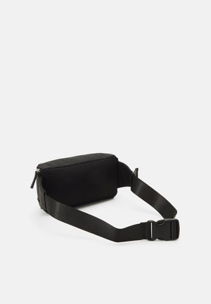Sac rectangulaire noir avec extérieur texturé et panneau en maille. Bretelle adjustable et fermeture zippée. Design compact adapté à un transport léger.