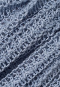 Hellblauer, gestrickter Stoff mit einem lockeren, strukturierten Muster. Die Fäden sind weich und leicht flaumig, wodurch ein zartes, luftiges Aussehen entsteht.