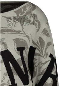 Pull gris avec un motif floral, de grandes lettres noires, et orné de strass argentés. Tissu en maille douce avec un col large.