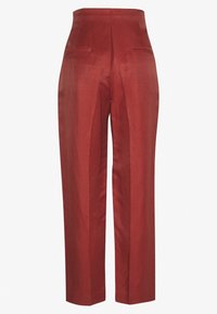 Pantaloni da donna a vita alta, dritti, di colore rosso ruggine, con pieghe frontali e due tasche a filetto posteriori, esposti su uno sfondo bianco semplice.