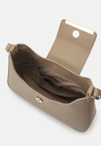 Sac bandoulière en cuir beige avec rabat ouvert, fermoir magnétique et une poche intérieure avec doublure en tissu et étiquette de marque.