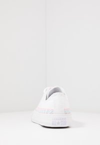 Baskets blanches en toile à coupe basse, dotées de surpiqûres en zigzag pastel, d'un talon texturé et d'une semelle en caoutchouc avec le logo "Converse All Star".