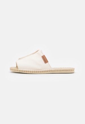 Płócienne klapki w kolorze off-white z otwartym noskiem, o teksturowanej tkaninie i plecionej podeszwie z juty z małą brązową metką.