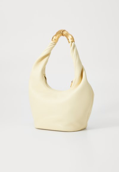 Τσάντα hobo σε απαλή, κρεμώδη κίτρινη δερμάτινη υφή με twisted χερούλι και χρυσές λεπτομέρειες. Λείο υλικό, στρογγυλή μορφή και ανοιχτός σχεδιασμός.