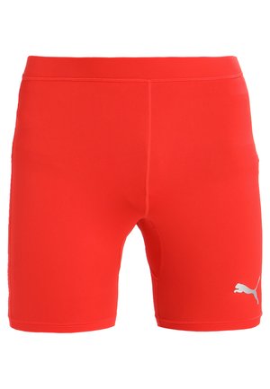 Red athletic shorts made of stretchy fabric with a smooth texture. Features a small white logo on the lower right leg. Mid-thigh length.