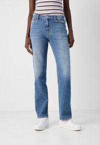 Blå denim jeans med rett benpassform, med en linning med knappelukking og subtil falming. Kombinert med hvite sneakers.