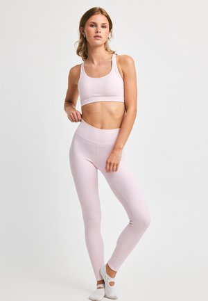 Lys rosa sports-bh og høyt liv leggings laget av glatt stoff, med sømløst design og en tettsittende silhuett.