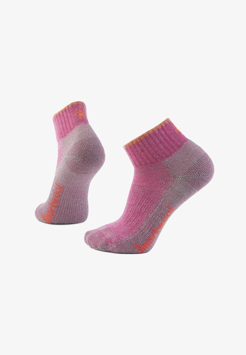 Calzini corti rosa e grigi con polsini a costina. La texture sembra lavorata a maglia con marchio arancione sul lato. Adatti per un abbigliamento casual.