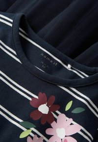 Granatowa koszula bawełniana w białe paski, okrągły dekolt, z kwiatowym nadrukiem w odcieniach różu, burgundów i zieleni. Miękka tekstura.