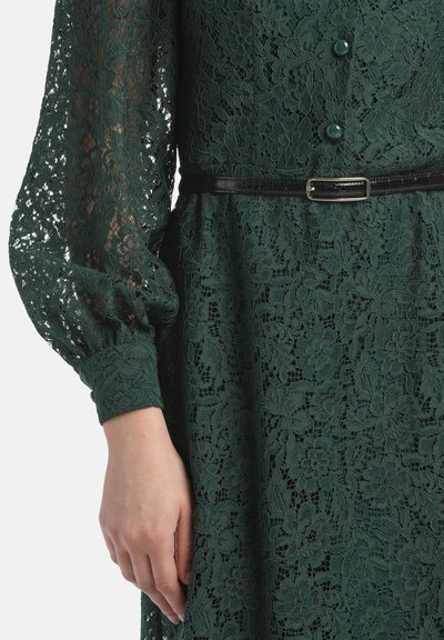 Dunkelgrünes Spitzenkleid mit floralen Mustern, langen Puffärmeln, Knopfdetails und einem schwarzen Gürtel mit rechteckiger Schnalle.