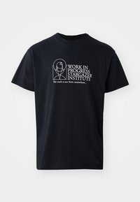 T-shirt de algodão preta com texto branco na frente: "INSTITUTO STARGAZER EM PROGRESSO" com um design ilustrado.