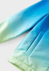 Giacca leggera con design a gradiente che va dal blu chiaro al verde. Tessuto morbido con tasca laterale e dettagli cuciti.