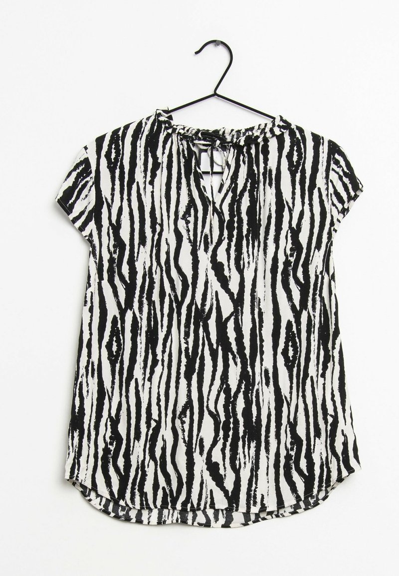 Blouse à manches courtes avec un motif zèbre noir et blanc, dotée d'un col rond et d'une légère coupe plus courte à l'avant. Texture de tissu douce.