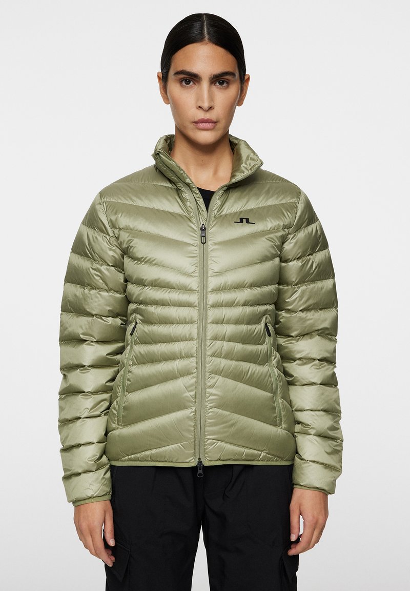 Vihreä puhuva takki, jossa on vaakasuora tikkaus, vetoketjullinen etuosa ja pystykaulus. Sisältää pienen mustan logon rinnassa ja sivutaskut.