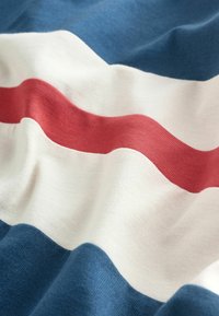 Țesătură de bumbac cu un model cu dungi ondulate în nuanțe de albastru marin, alb și roșu. Textură moale cu un contrast de culori pronunțat.