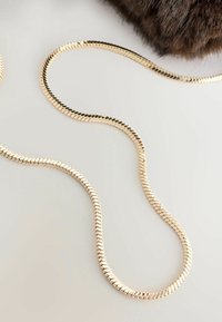 Guldfarvet slangekæde i en glat, flad design. Har en fleksibel, blank tekstur, der forstærker dets elegante udseende.