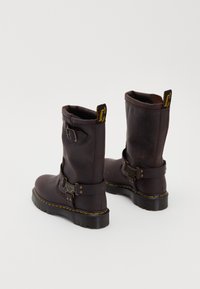 Brown leather ankle boots with a buckle strap, yellow stitching, and a textured sole. The upper is slightly slouched with a reinforced toe.