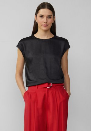 Zwarte top met korte mouwen van gladde stof, met een ronde hals en een ontspannen pasvorm. Gecombineerd met hoge rode broek.