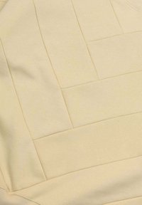 Tessuto beige testurizzato con un design trapuntato caratterizzato da pannelli rettangolari. Materiale morbido con una leggera lucentezza, che crea un effetto visivo moderno.