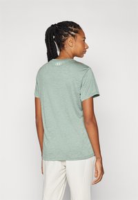 Grønn melert t-skjorte med korte ermer og rund hals, med Under Armour-logo på baksiden. Myk tekstur, standard passform, avslappet design.