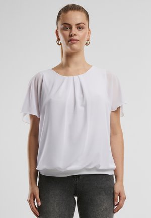 White short-sleeve top with a pleated design, soft fabric, rounded neckline, and relaxed fit, paired with dark jeans. Lightweight and flowy.