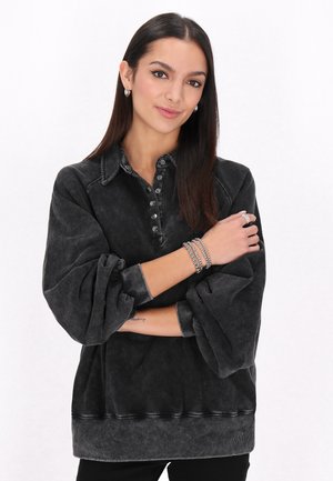Felpa grigio scuro con collo a camicia, patta con sei bottoni e polsini elasticizzati. Presenta una vestibilità comoda e un tessuto testurizzato.