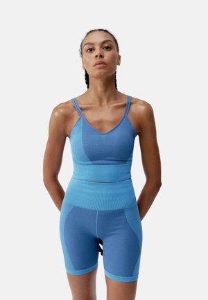 Blue activewear set featuring a ribbed crop top with thin straps and high-waisted shorts. The fabric has a textured pattern and smooth finish.