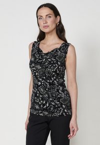 Haut sans manches noir avec un motif floral et de papillons blanc complexe, présentant un décolleté drapé et un tissu texturé.