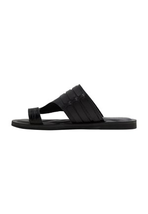 Black open-toe slide sandal with a wide strap featuring three vertical bands and a toe loop, flat sole, side view.