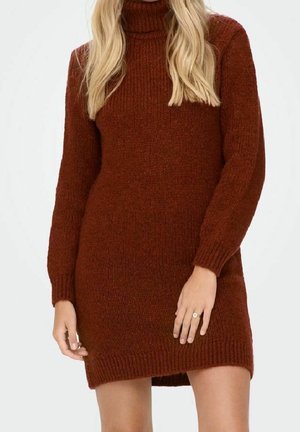 Vrouw draagt een roestkleurige, langarmige, gebreide coltrui-jurk, die tot halverwege de dijen reikt en een gestructureerde stof heeft.