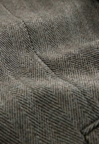 Teksturowana tkanina w jodełkę w odcieniach brązu i szarości, charakteryzująca się gładką powierzchnią o subtelnej głębi i rytmicznym wzorze.
