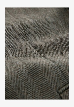 Kareeritud kalasaba kangas pruunides ja hallides toonides, millel on sile pind koos vaevu märgatava sügavuse ja rütmilise mustriga.