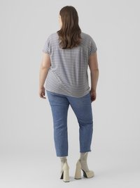 Ριγέ μπλουζάκι με κοντά μανίκια σε γκρι και λευκό χρώμα, συνδυασμένο με μπλε τζιν παντελόνι μέχρι τον αστράγαλο. Μπεζ παπούτσια με ψηλό τακούνι και ανοιχτογκρι κάλτσες με ραβδωτή υφή.