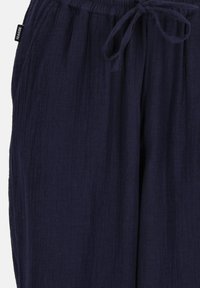 Marineblaue, leichte Hosen aus einem strukturierten, knitternden Stoff. Ausgestattet mit einem elastischen Bund und einer Kordel zur individuellen Anpassung.