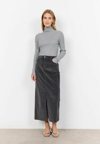 Maglione grigio a coste con collo alto abbinato a una gonna maxi in corda grigia scura con uno spacco frontale, indossato con sandali con tacco in argento.