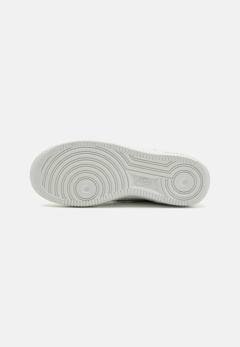 Suola di sneaker bianca in gomma con un motivo di battistrada circolare, bordi testurizzati e un dettaglio circolare centrale. Logo Nike impresso vicino al tallone.