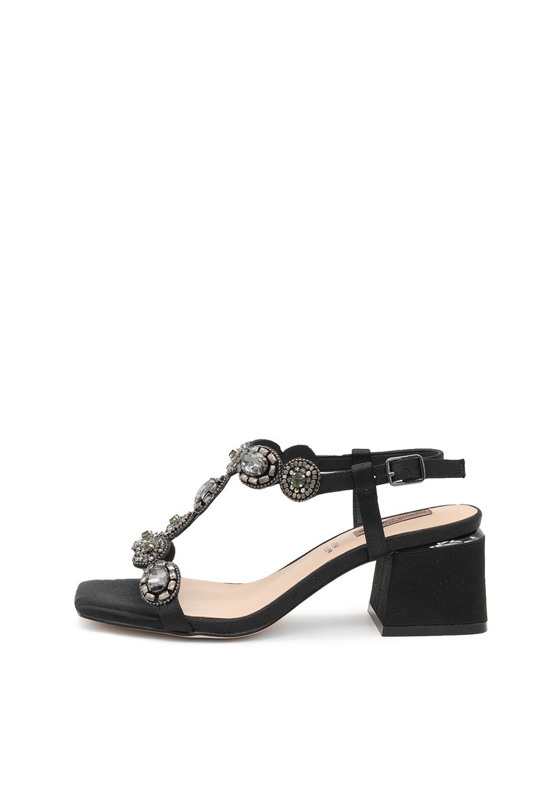 Sandali neri con tacco a blocco. Presentano un design a T decorato con pietre decorative e una cinghia alla caviglia regolabile. Texture morbida.