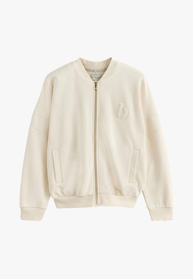 Veste bomber beige à fermeture éclair avec col, poignets et ourlet côtelés, deux poches avant et un logo brodé discret sur la poitrine gauche.