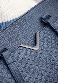 Dark blue textured synthetic handbag featuring a quilted pattern, sleek gray hardware accent, and adjustable strap details.