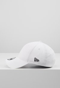 Weißer Baseball-Cap aus Baumwolle, mit einem schwarzen gestickten Logo auf der Vorderseite, gebogenem Schirm und belüfteten Ösen.