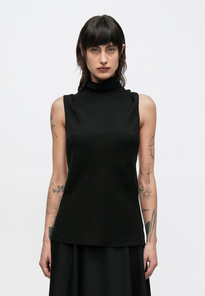 Černý top bez rukávů s vysokým límcem, s hladkou texturou a jemným puntíkovaným vzorem. Jednoduchý, čistý design, vhodný pro vrstvení.