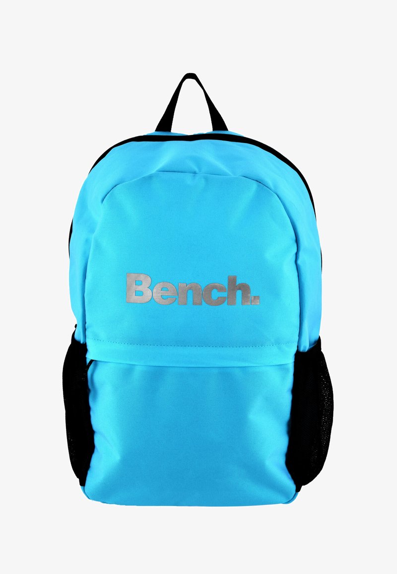 Mochila azul claro con el logo plateado "Bench.", estructura acolchada, bolsillos laterales de malla negra y asa superior para facilitar el transporte.
