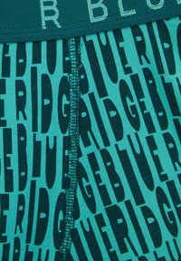 Męskie bokserki w kolorze teal z czarnymi, dużymi nadrukami. Miękka tkanina z przeszyciem z przodu.