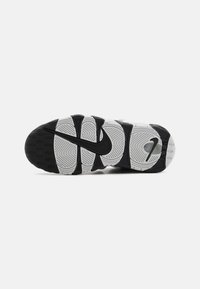 Nike'i tossu põhi, millel on mustvalge disain, tekstureeritud kummimuster ja silmapaistva musta swoosh-logo keskmisel osal.
