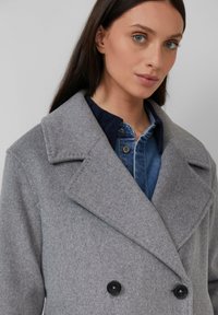 Grijze wolmix dubbele-breasted coat met grote revers en twee zwarte knopen, gedragen over een blauwe denimshirt. Gladde textuur. Casual ontwerp.