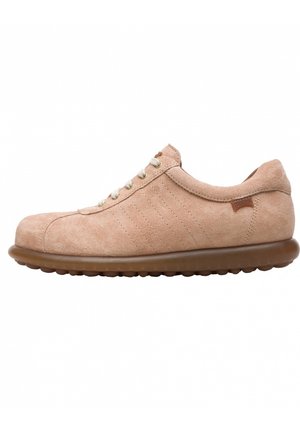 Zapatilla de ante beige con punta redonda, cuello curvado y rayas laterales texturizadas. Presenta cordones crema y una suela de goma marrón.